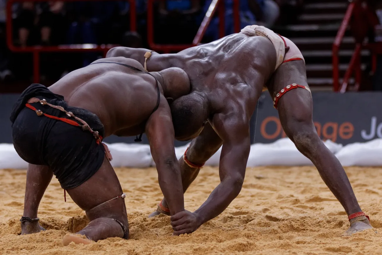 Luchadores de lutte sénégalaise en combate tradicional sobre arena