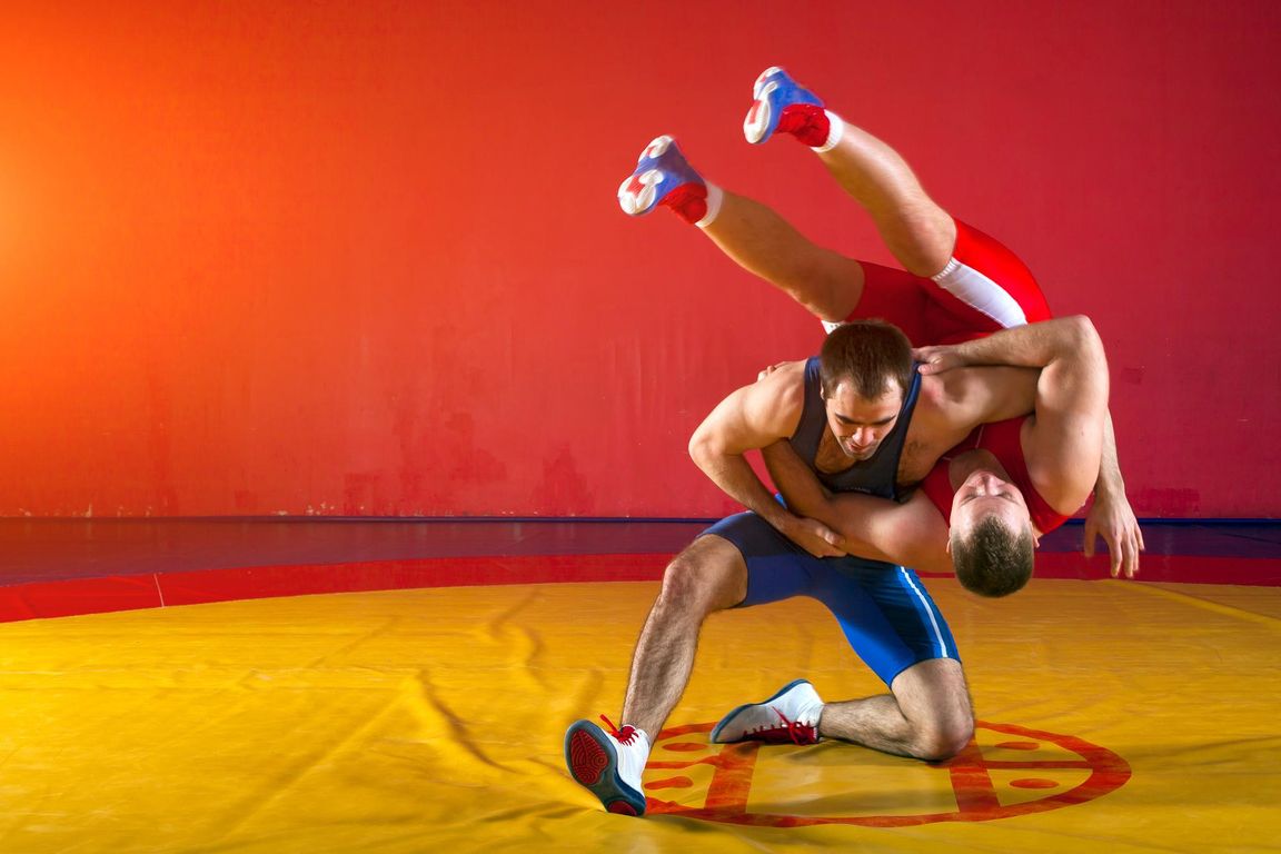 Dos luchadores practicando una proyección en un tapiz de lucha